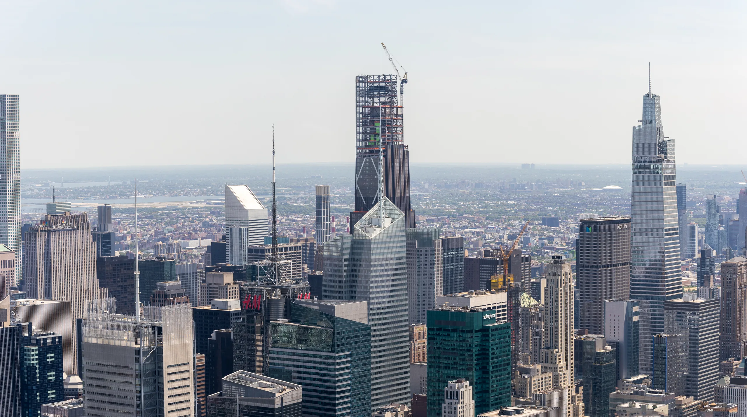 A wide daylight view across Midtown Manhattan, construction cranes standing among the towers on the skyline.